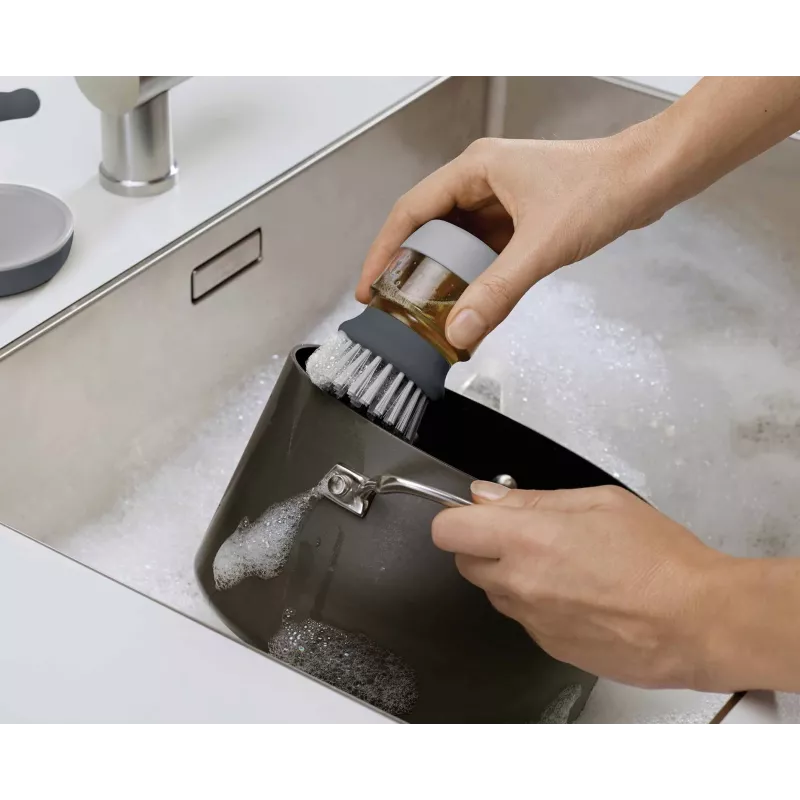 Joseph Joseph Palm Scrub Grey indų plovimo šepetys su integruotu muilo dozatoriumi